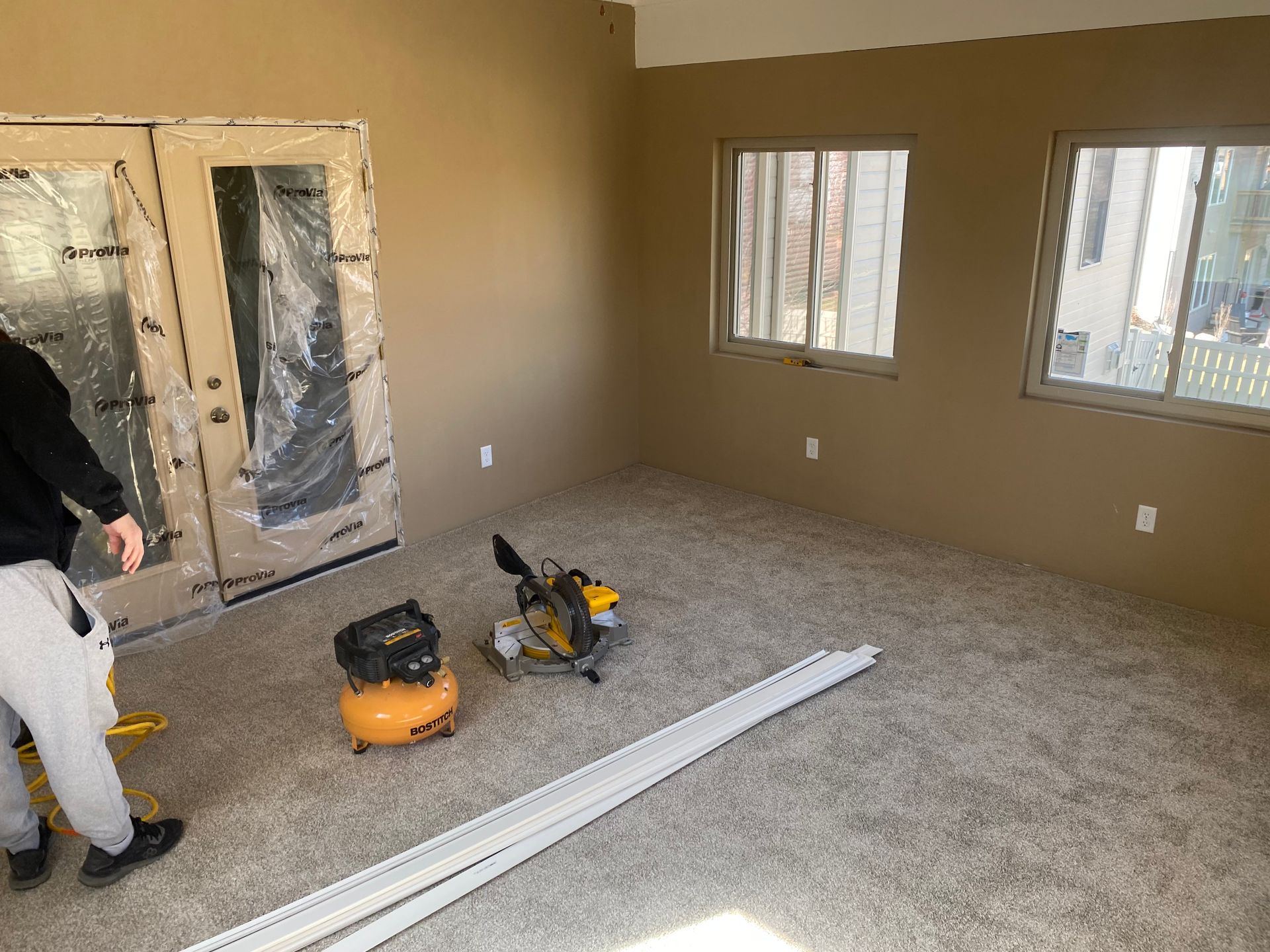 A man is standing in an empty room with tools on the floor.