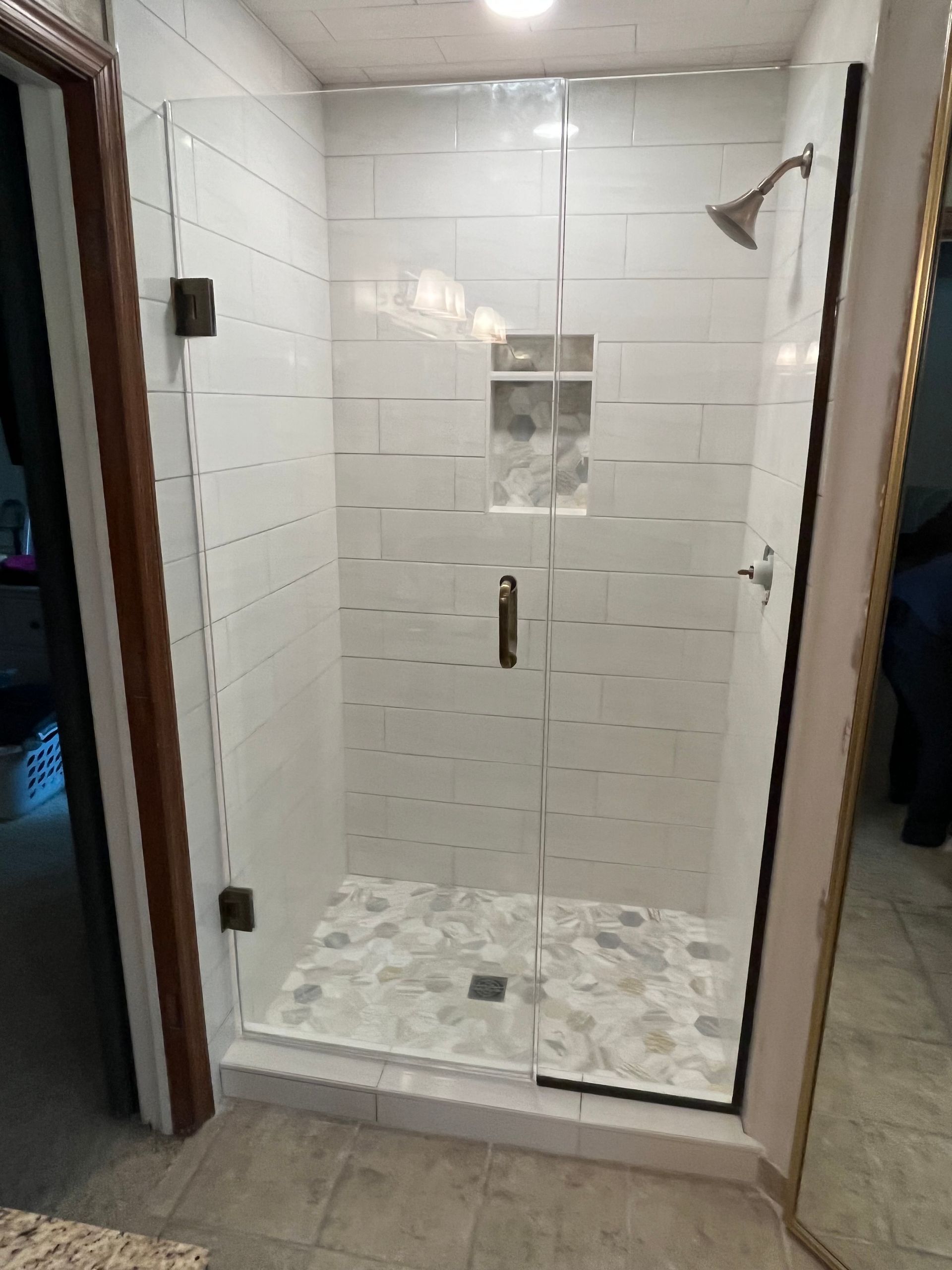 A bathroom with a walk in shower with a glass door.