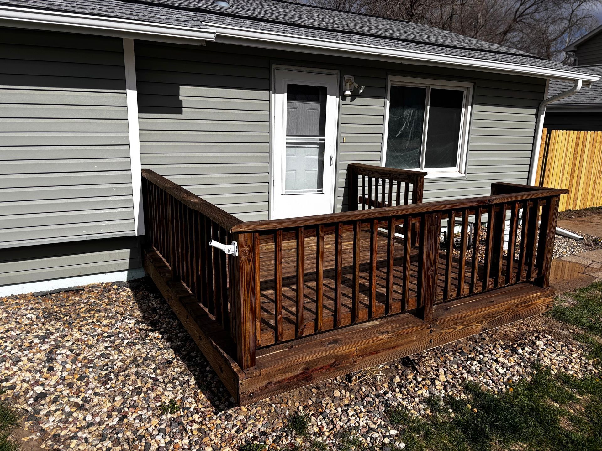 A small house with a wooden deck in front of it.
