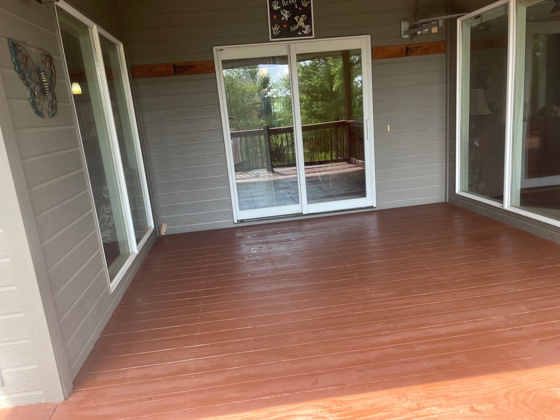 A porch with sliding glass doors and a wooden floor.