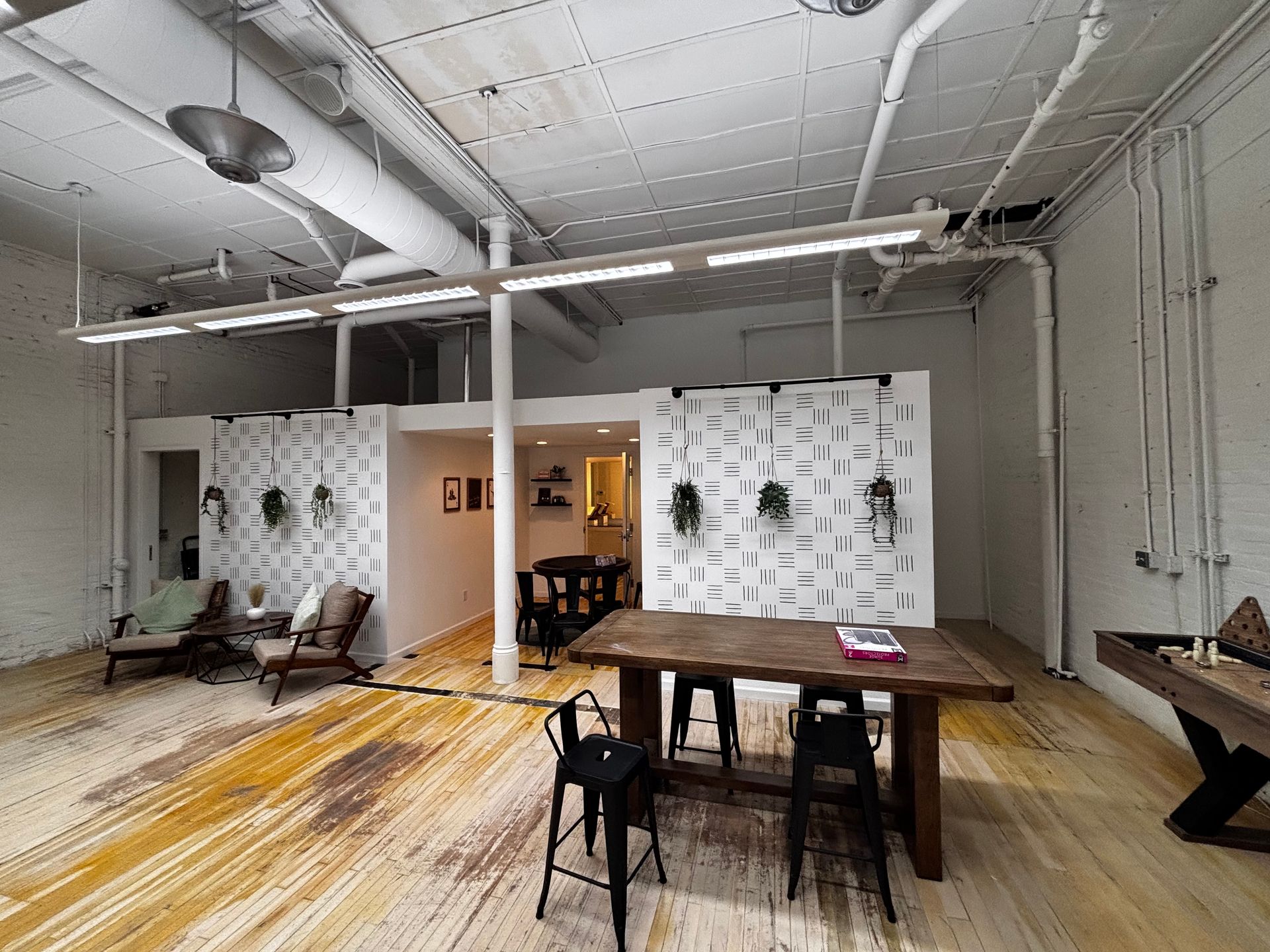 Bright loft with wood floors, a large table, seating area, and dividers.