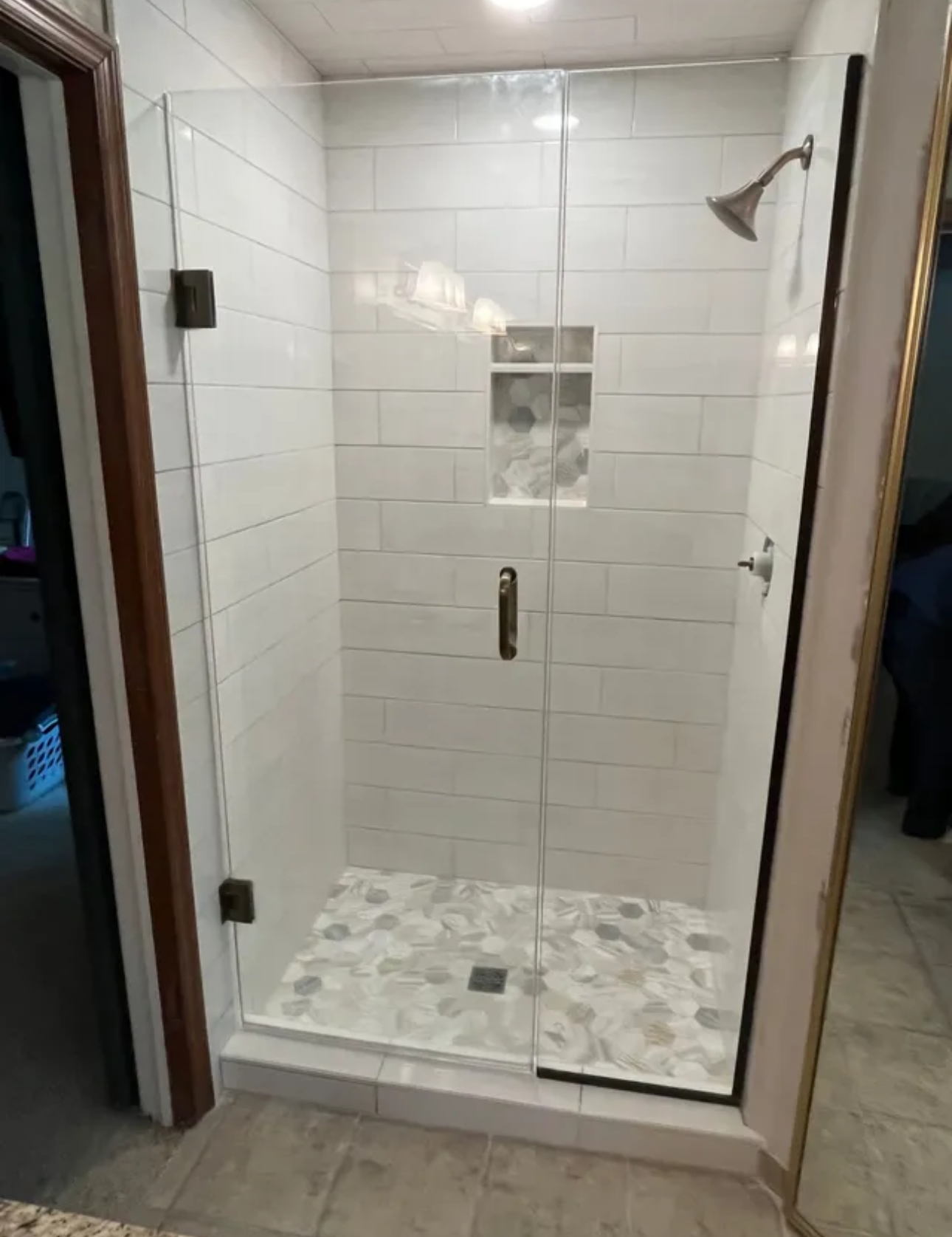 A bathroom with a walk-in shower with a glass door.