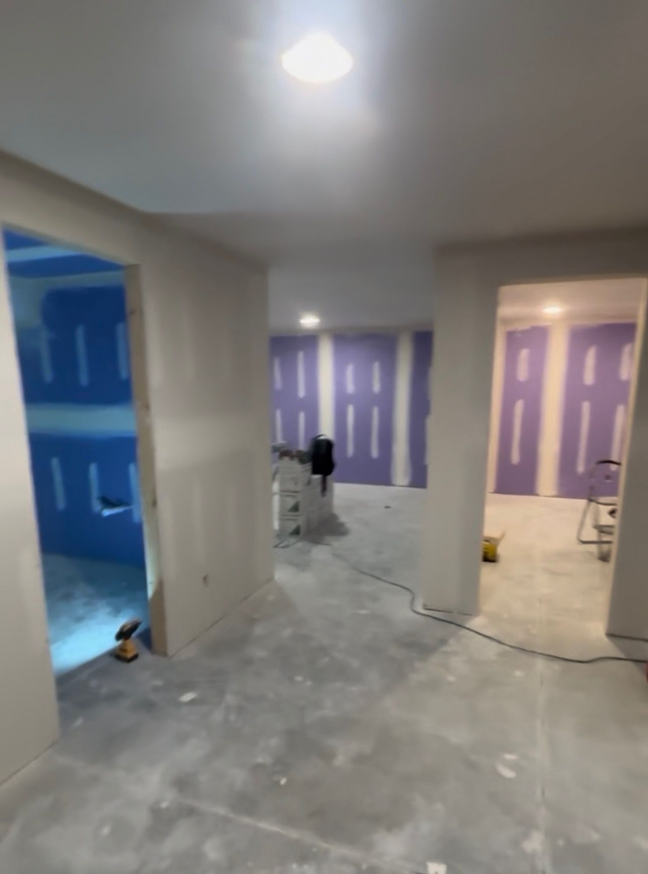 Interior construction scene with open doorways, drywall, and unfinished surfaces.