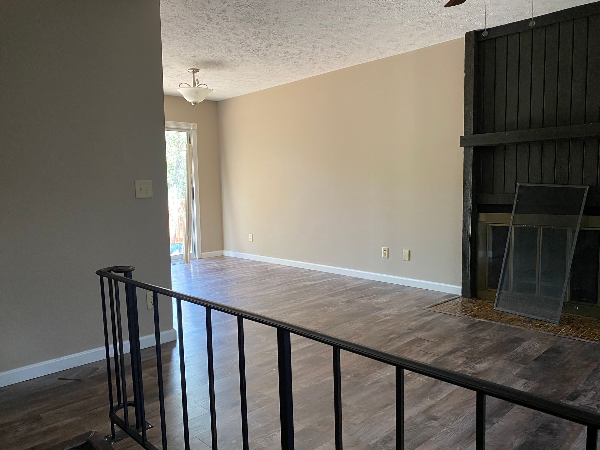 An empty living room with hardwood floors and a fireplace.