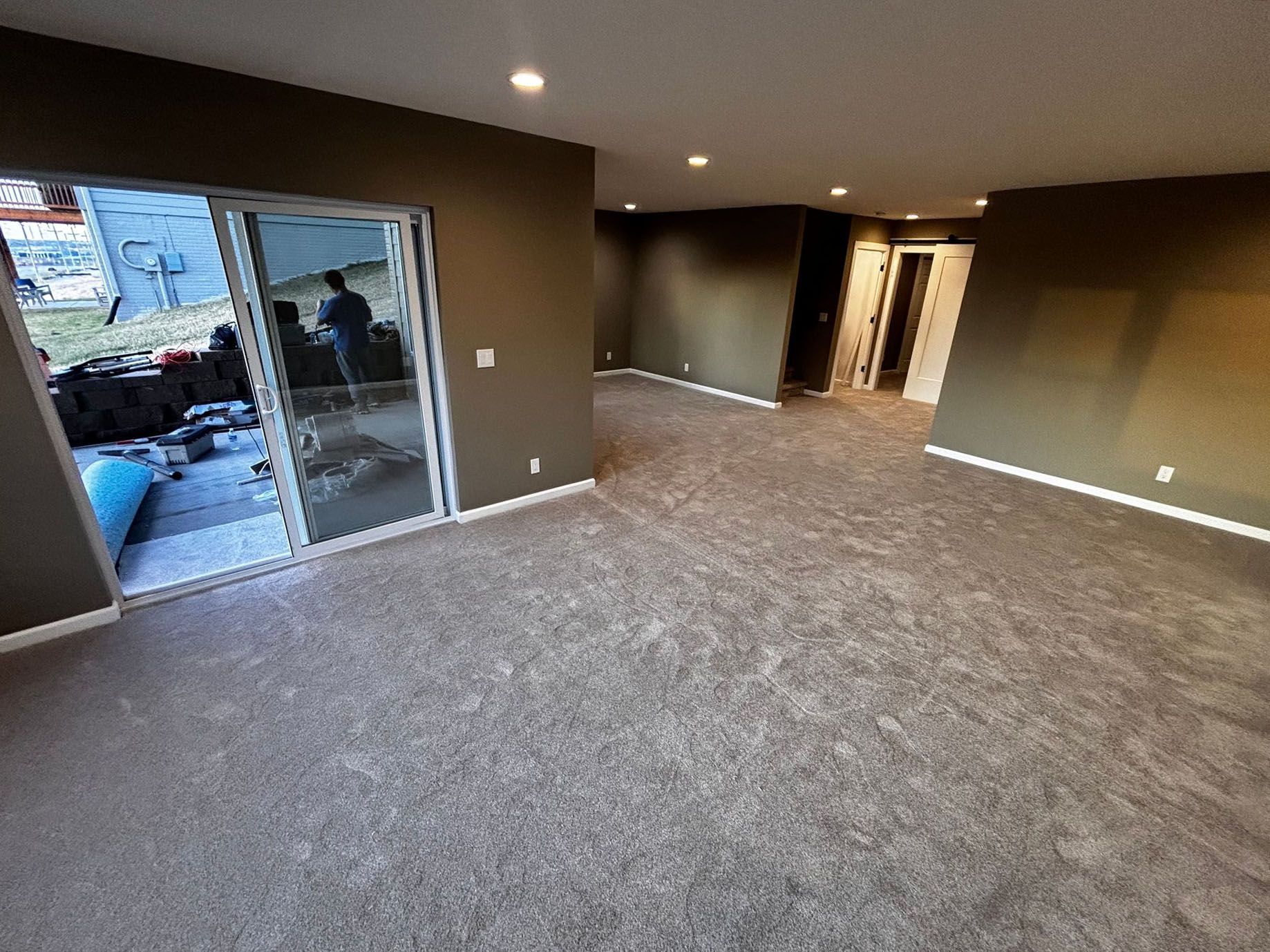 A living room with a sliding glass door and a carpeted floor.