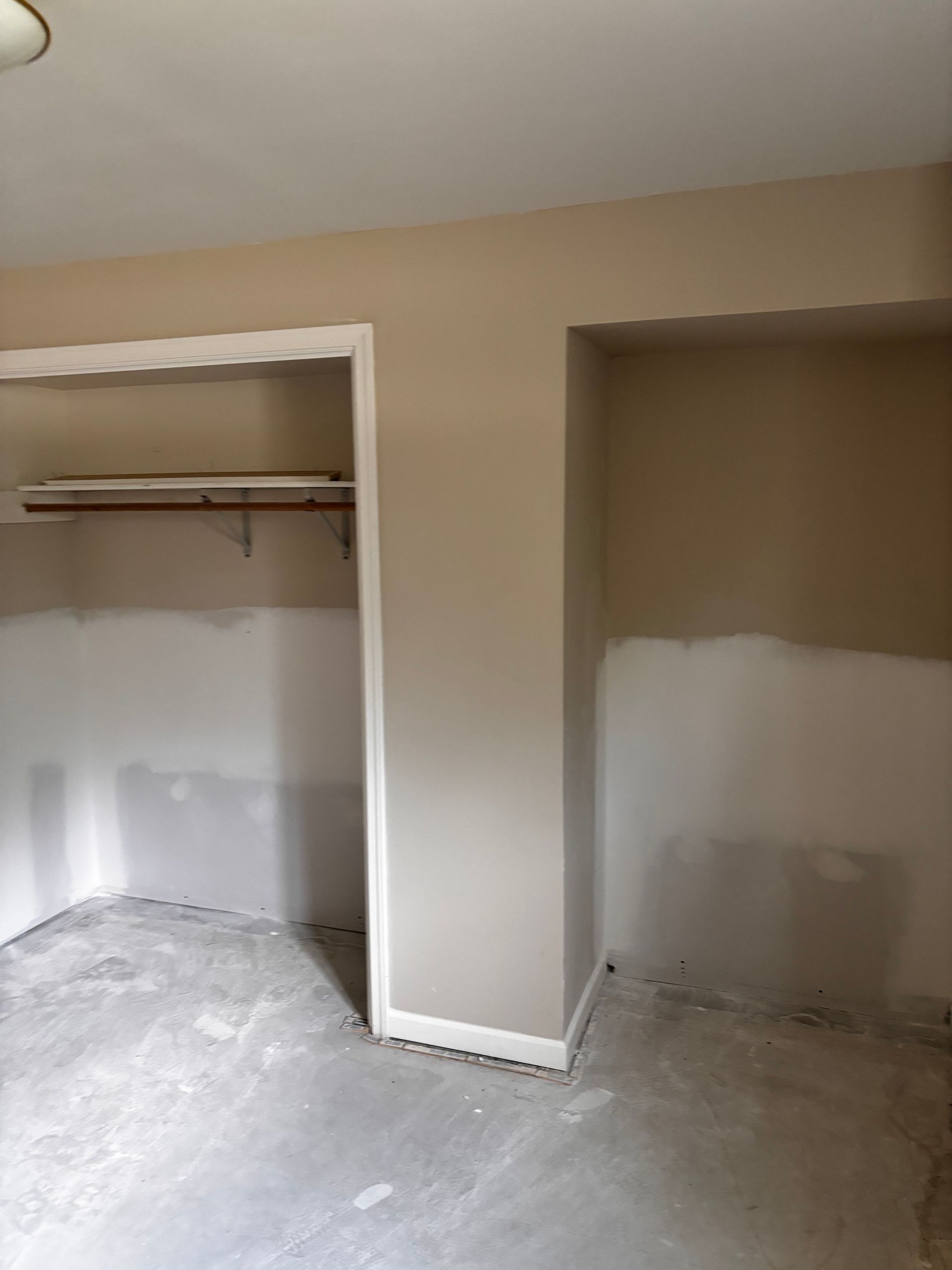 An empty closet with a shelf in the middle of it.