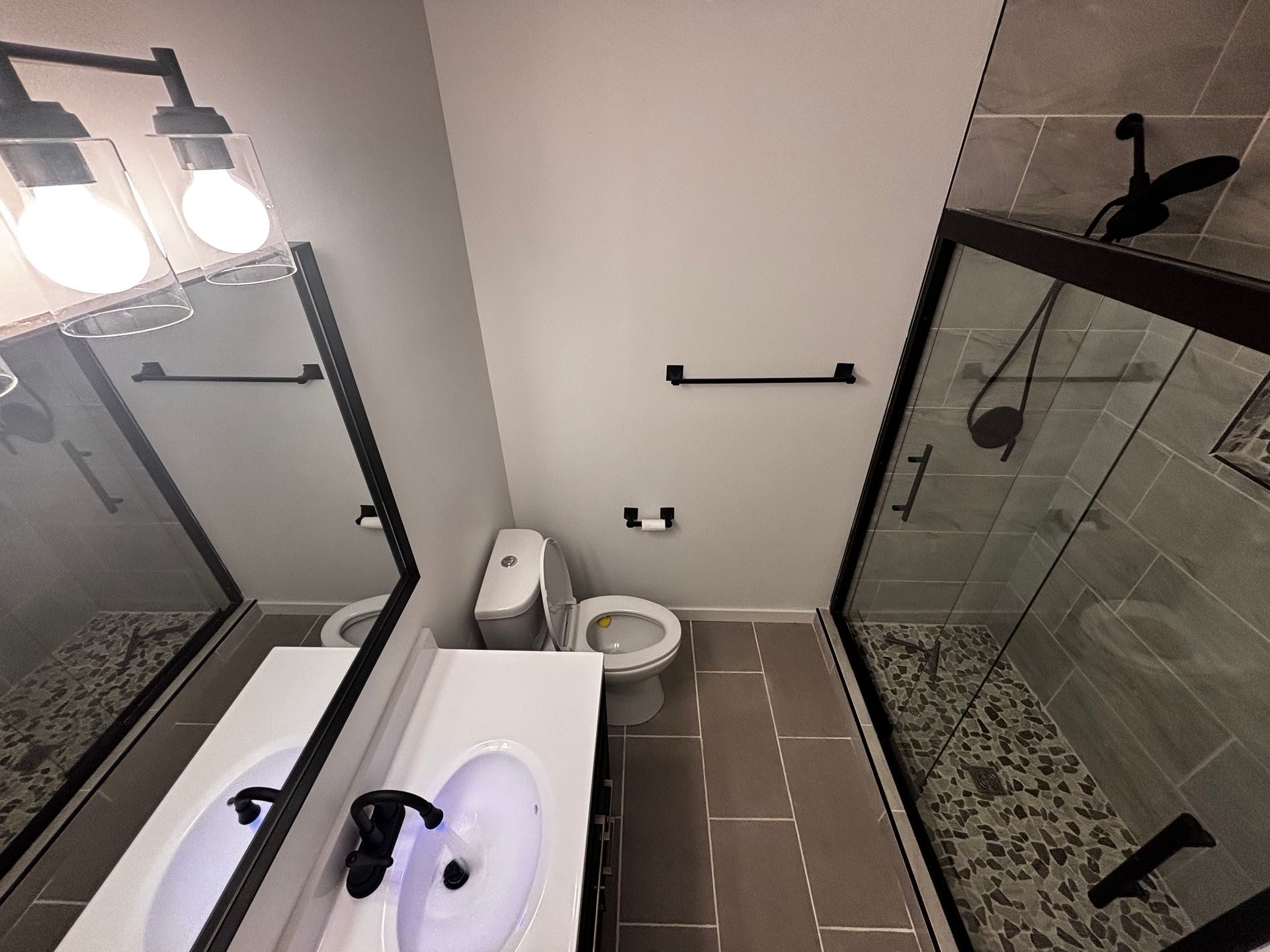 A bathroom with a toilet , sink and shower.