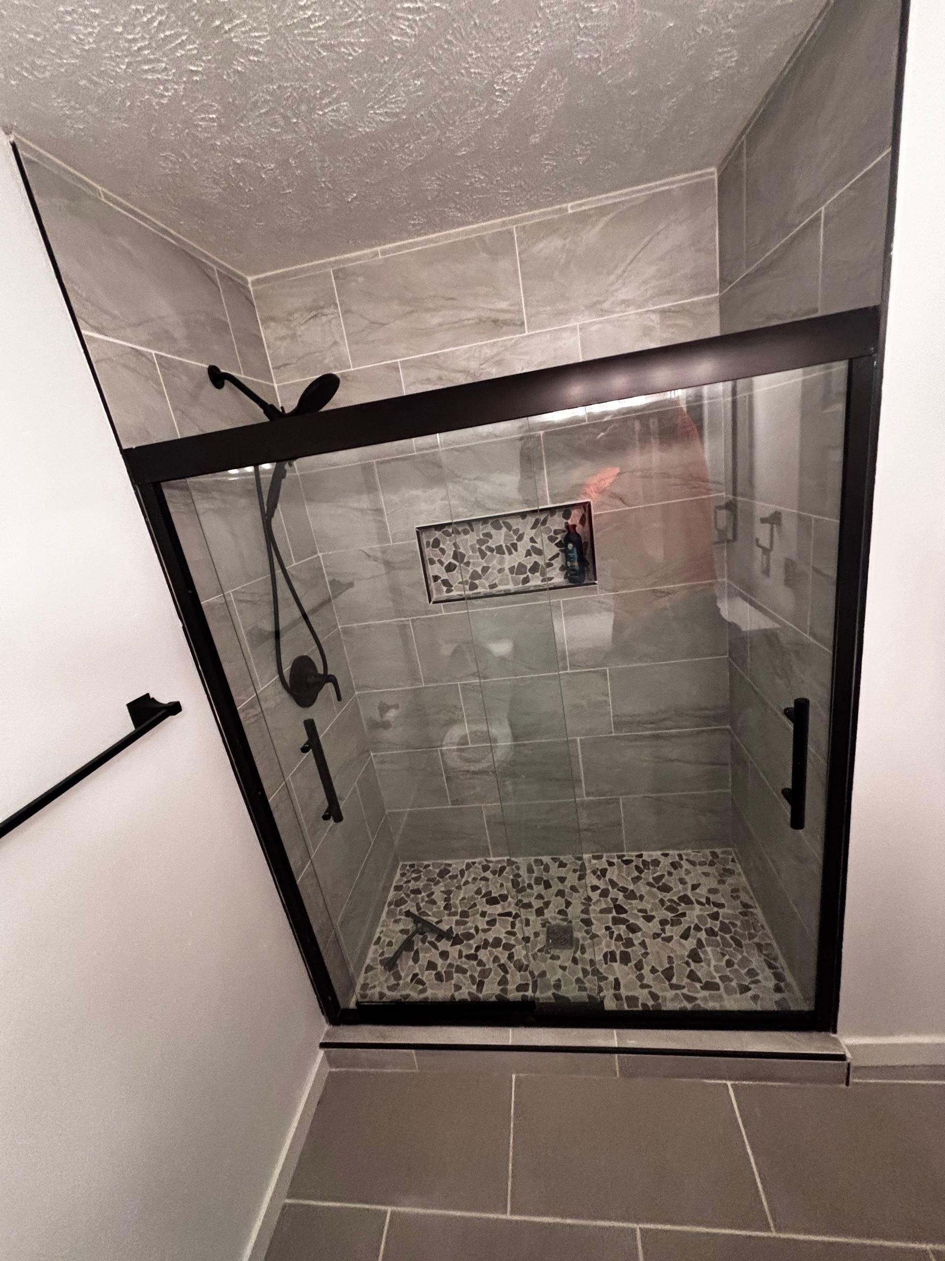 A bathroom with a walk in shower with a black frame.