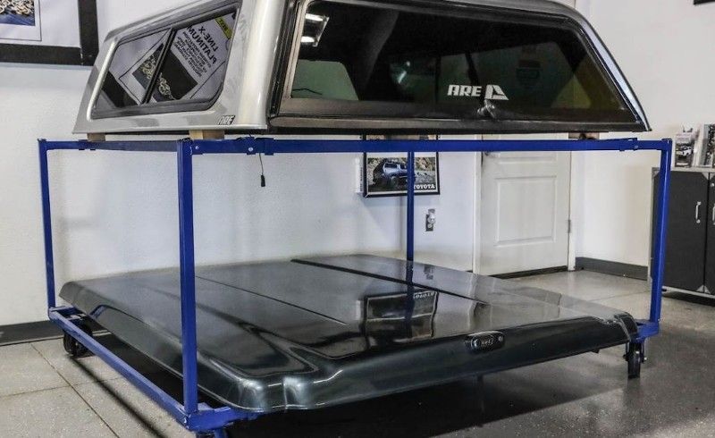 A truck canopy is sitting on top of a blue cart