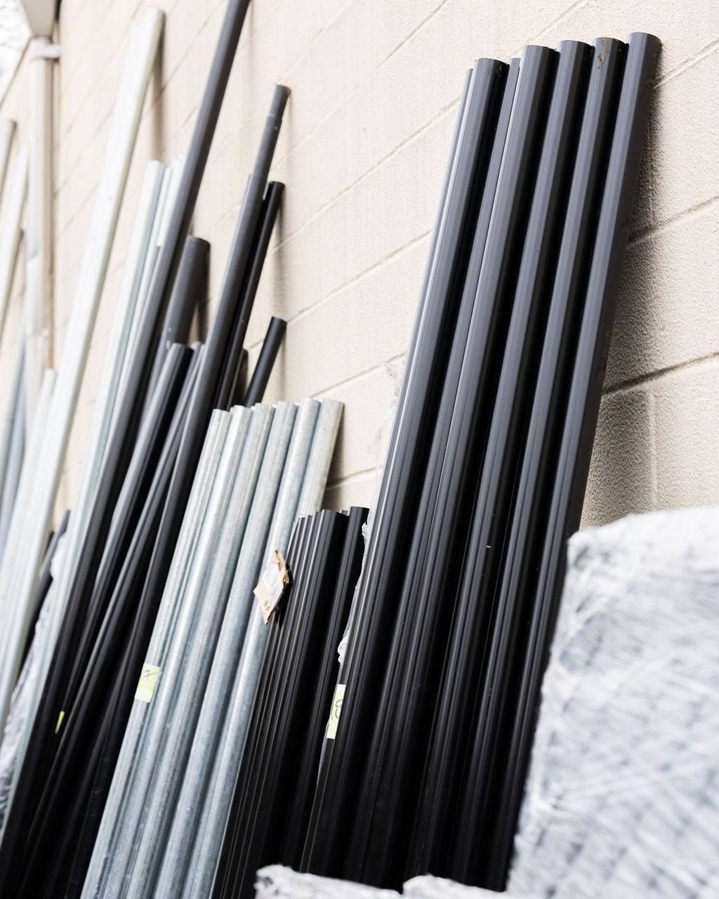Black metal poles leaning against a light beige wall.