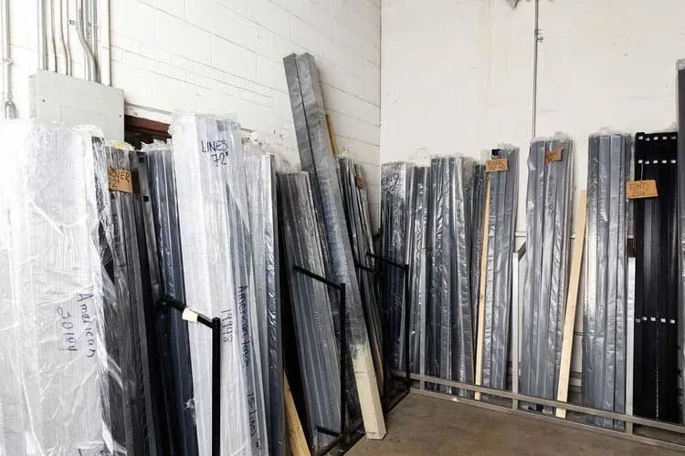 Shelves of wrapped window and door frames in a warehouse setting.