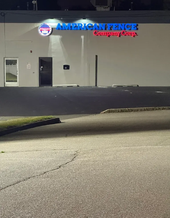 Night view of American Fence Company storefront with lit sign and empty parking lot