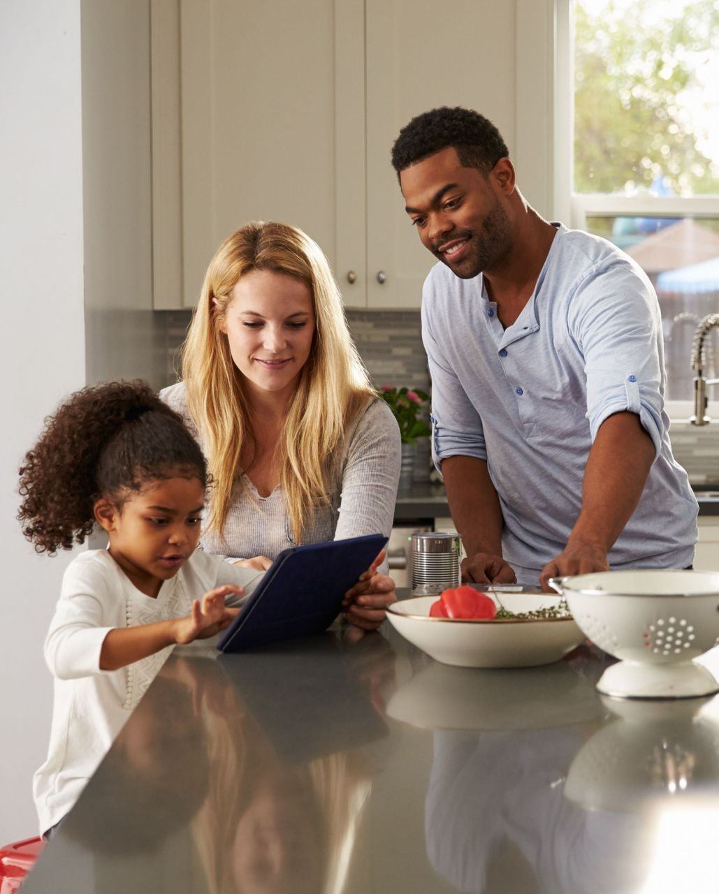 family in kitchen looking at ipad