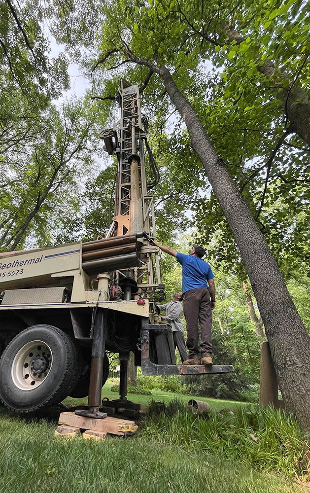 A man is standing on top of a truck next to a tree.