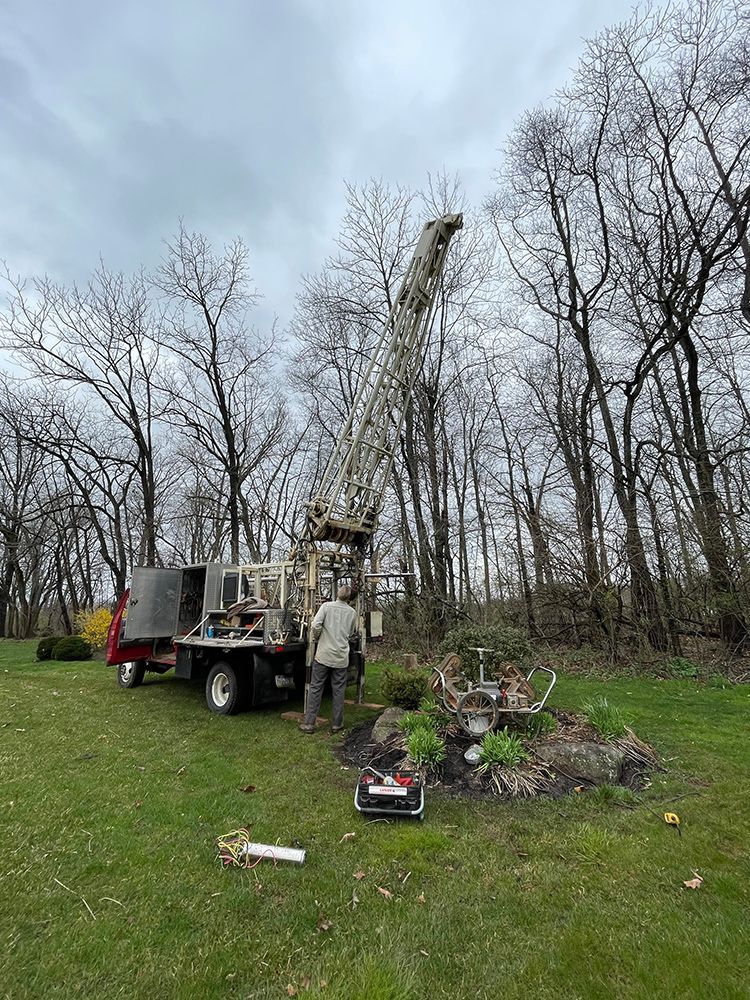 A man is standing next to a crane in a grassy field.
