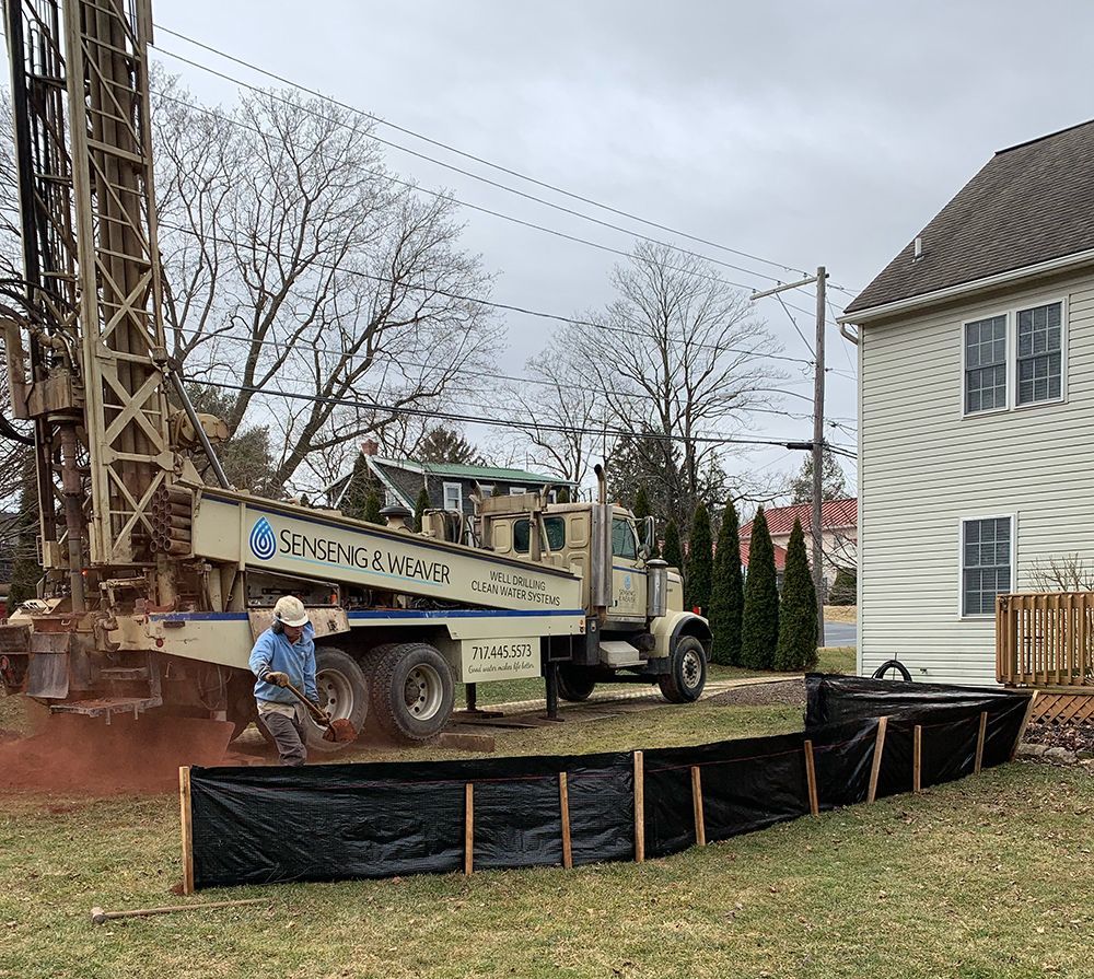 A man is sitting on the back of a truck in front of a house.