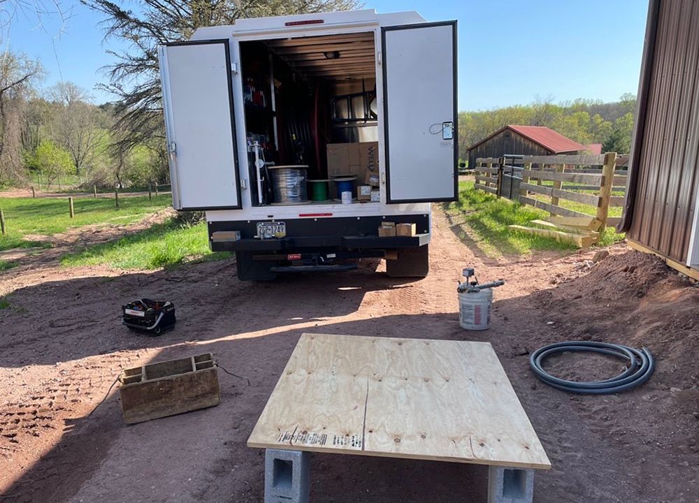 A white truck is parked on a dirt road next to a wooden table.