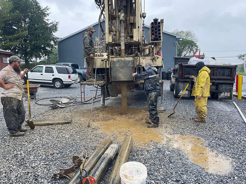 A group of men are working on a drilling rig in a gravel lot.