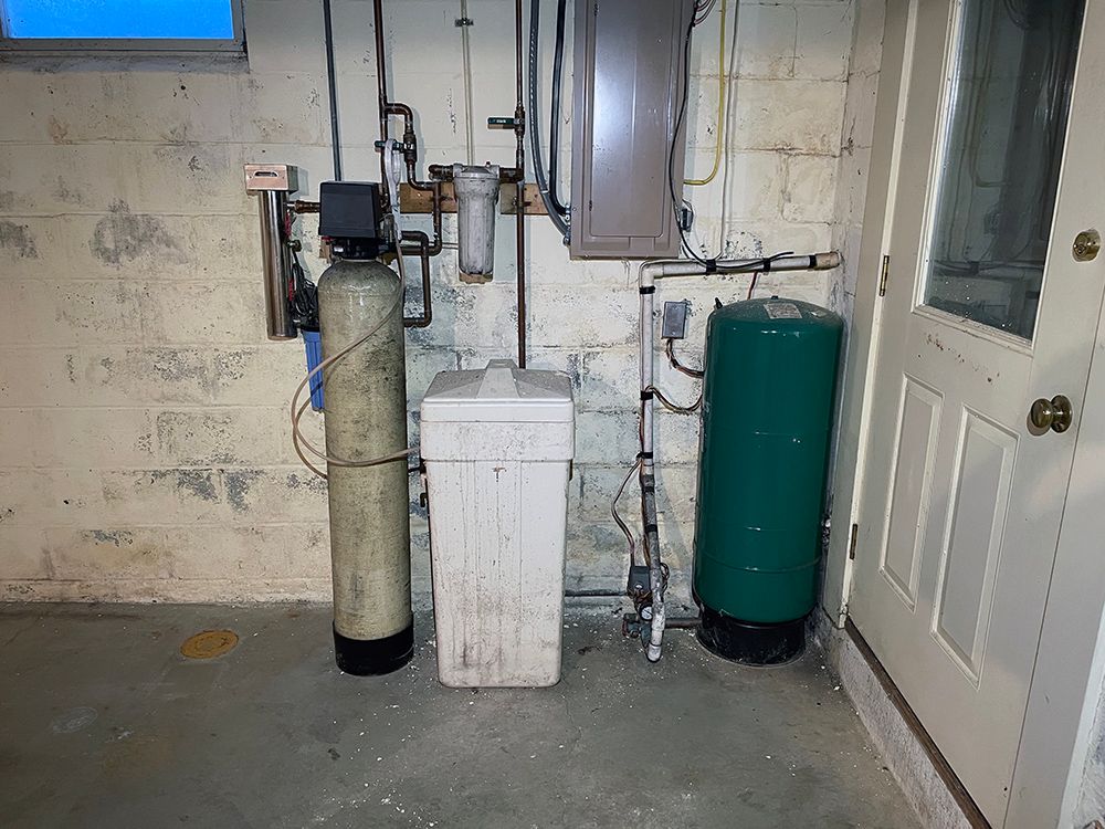 A room with a water filter and a green tank