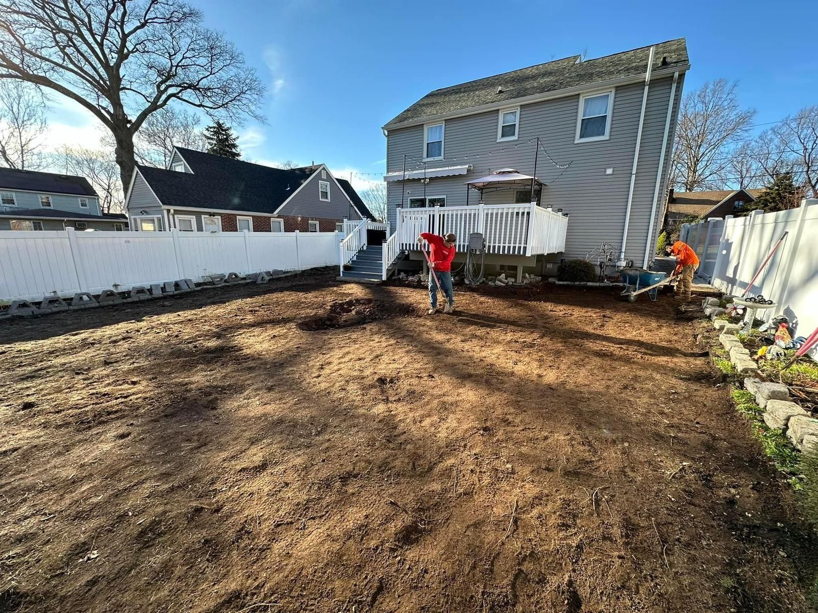 A man is standing in a dirt yard in front of a house.