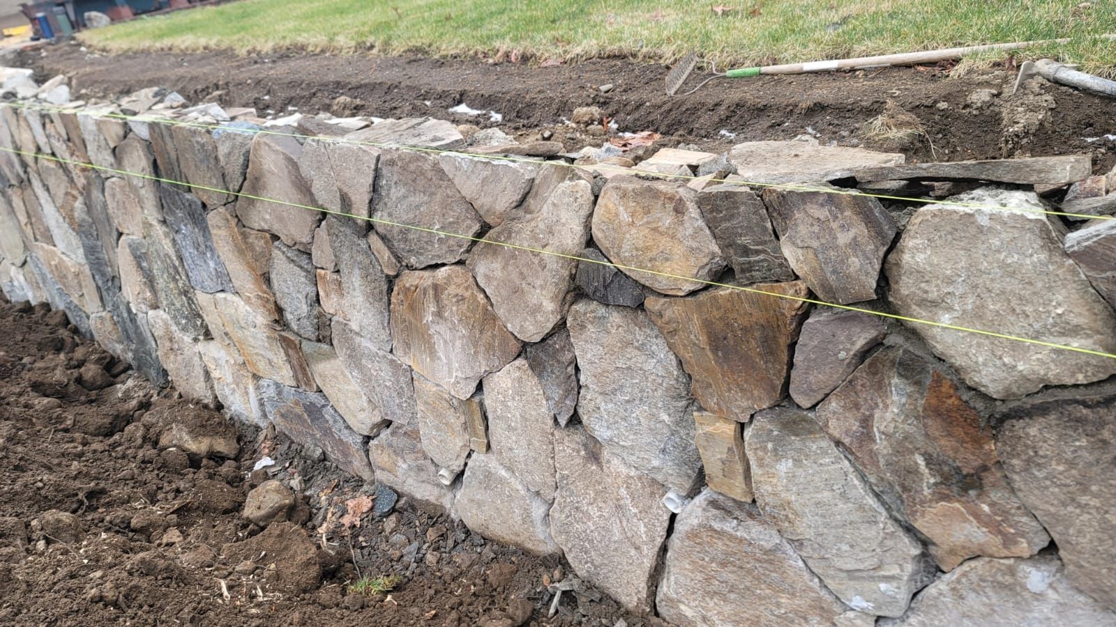 A stone wall is being built in a yard.