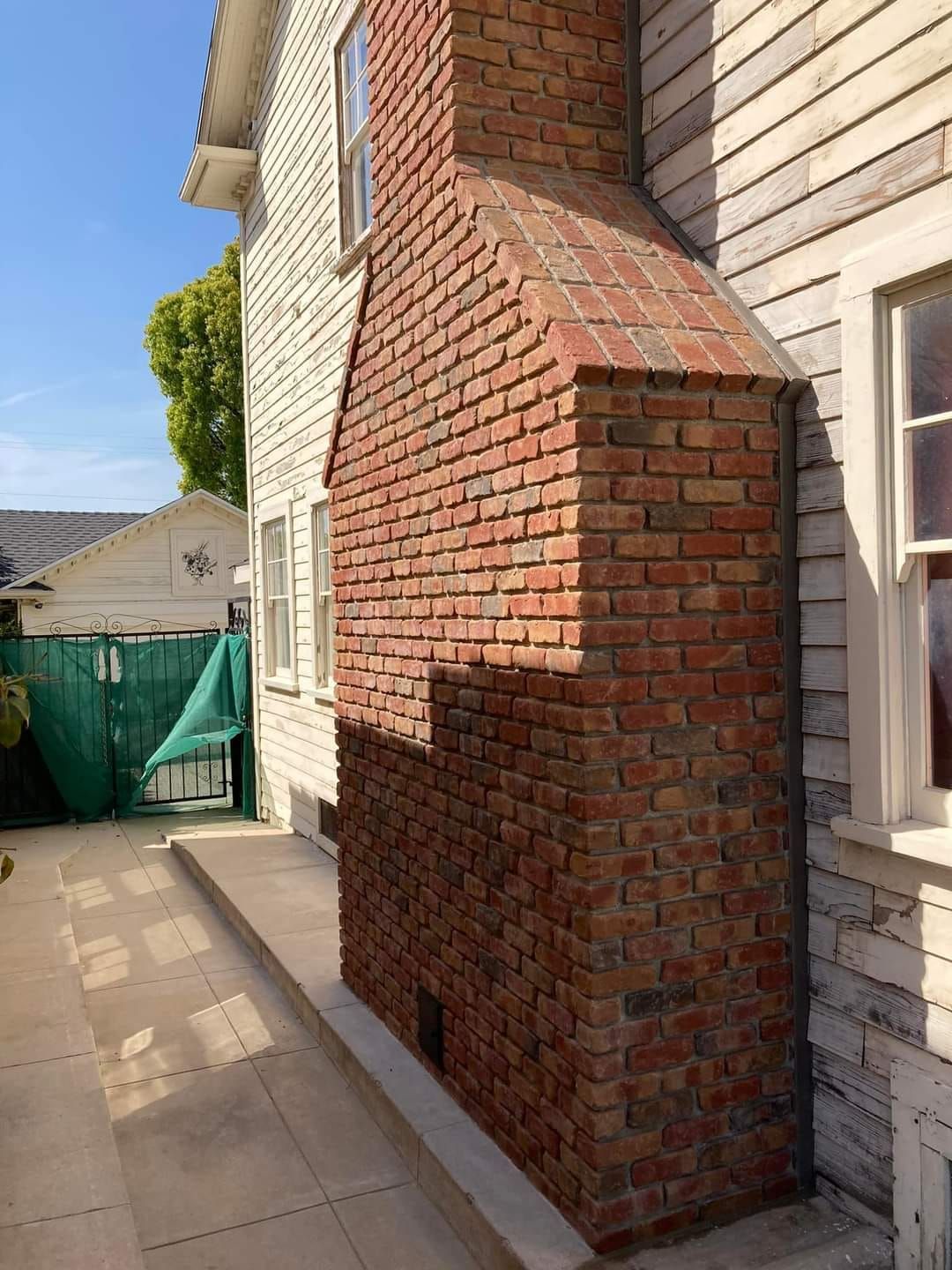 A brick chimney is on the side of a white house.
