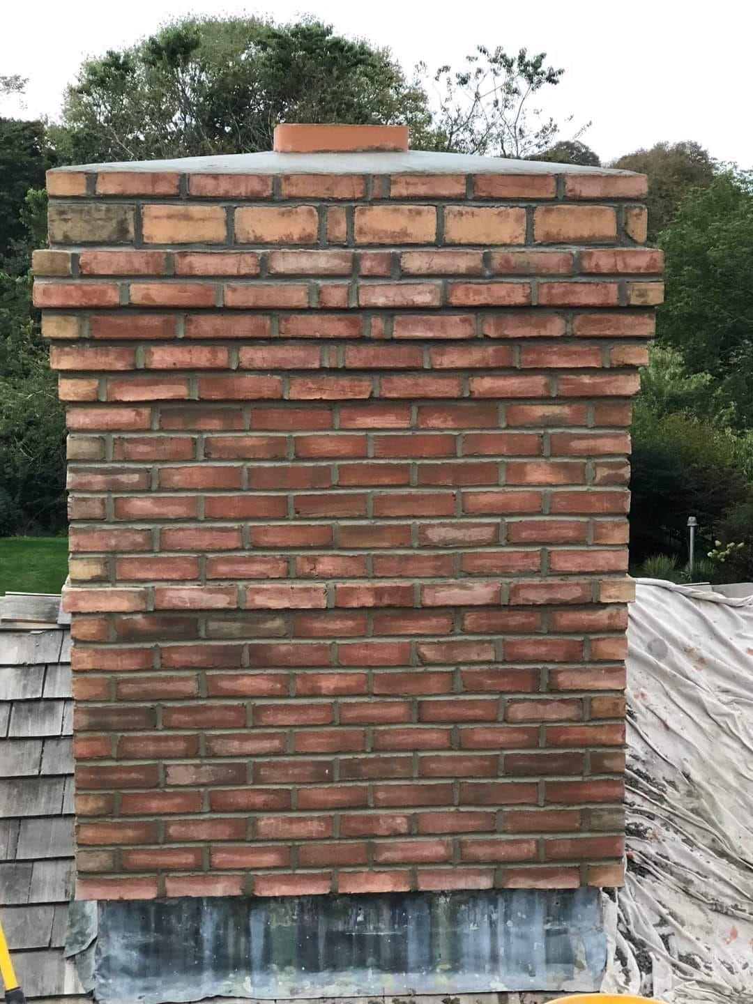 A brick chimney is being built on top of a dirt field.