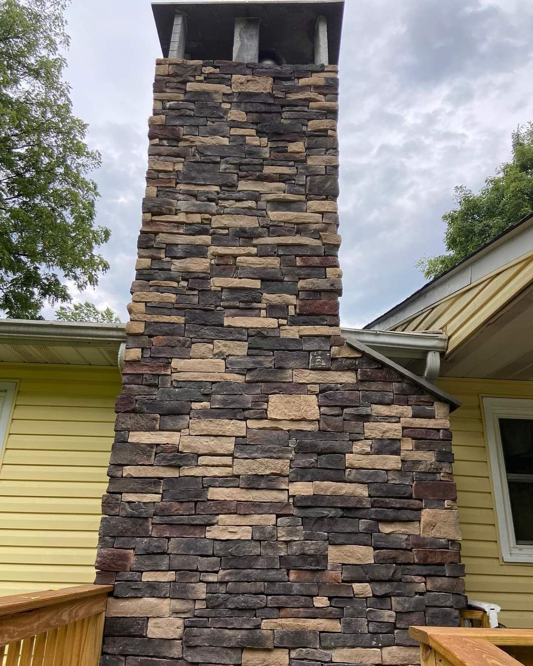 A large brick chimney is on the side of a house.