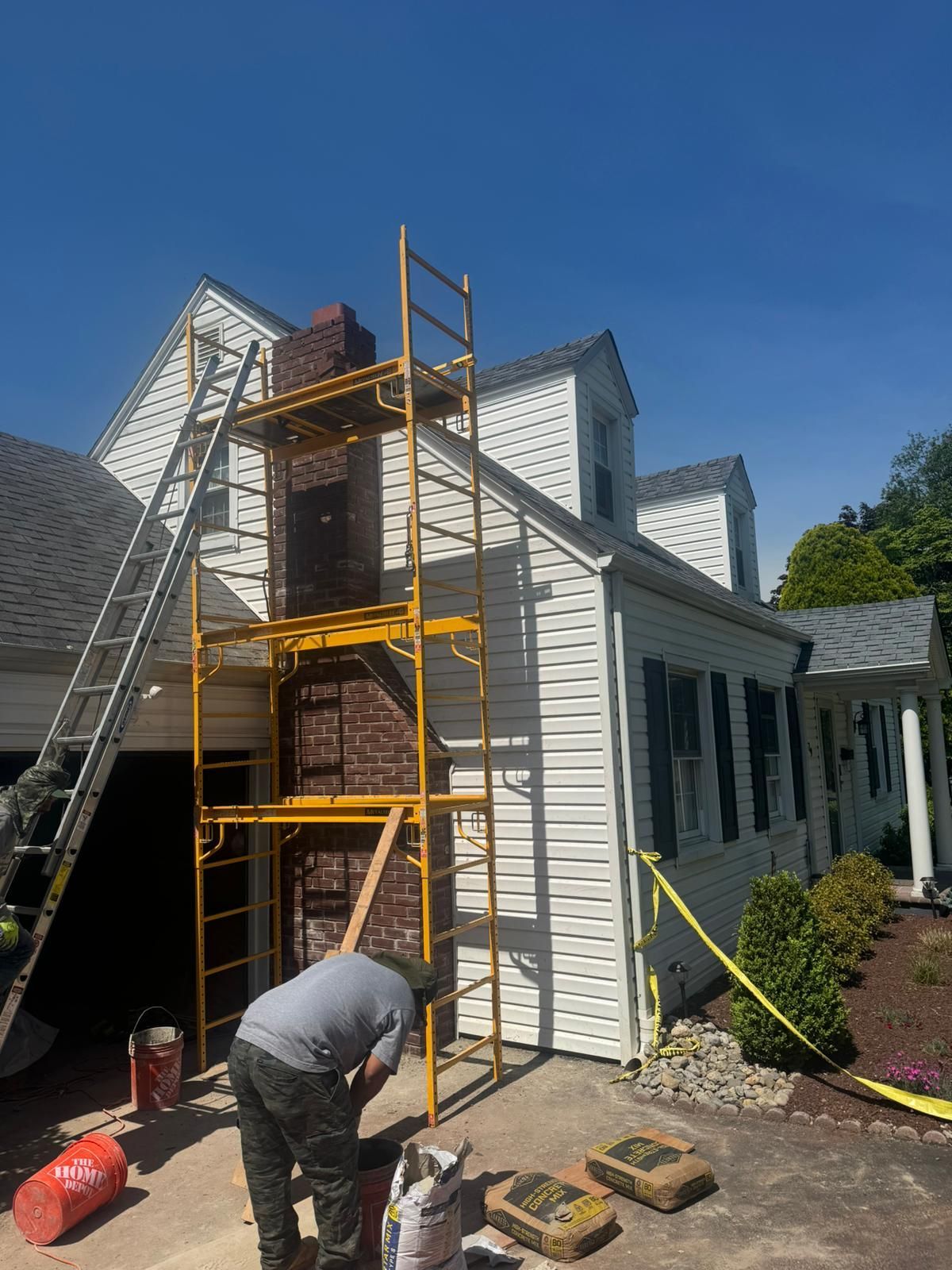 A man is working on a chimney on the side of a house.