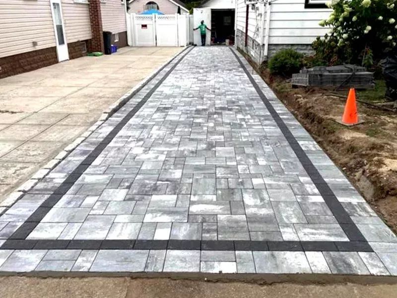 A brick driveway is being built in front of a house.