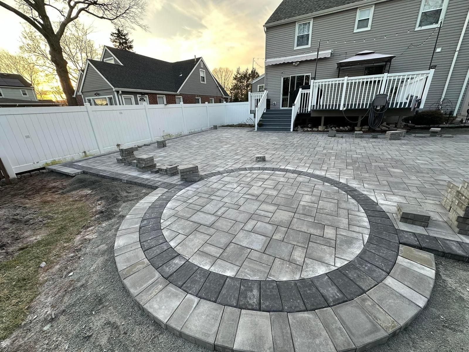 A circular patio is being built in the backyard of a house.