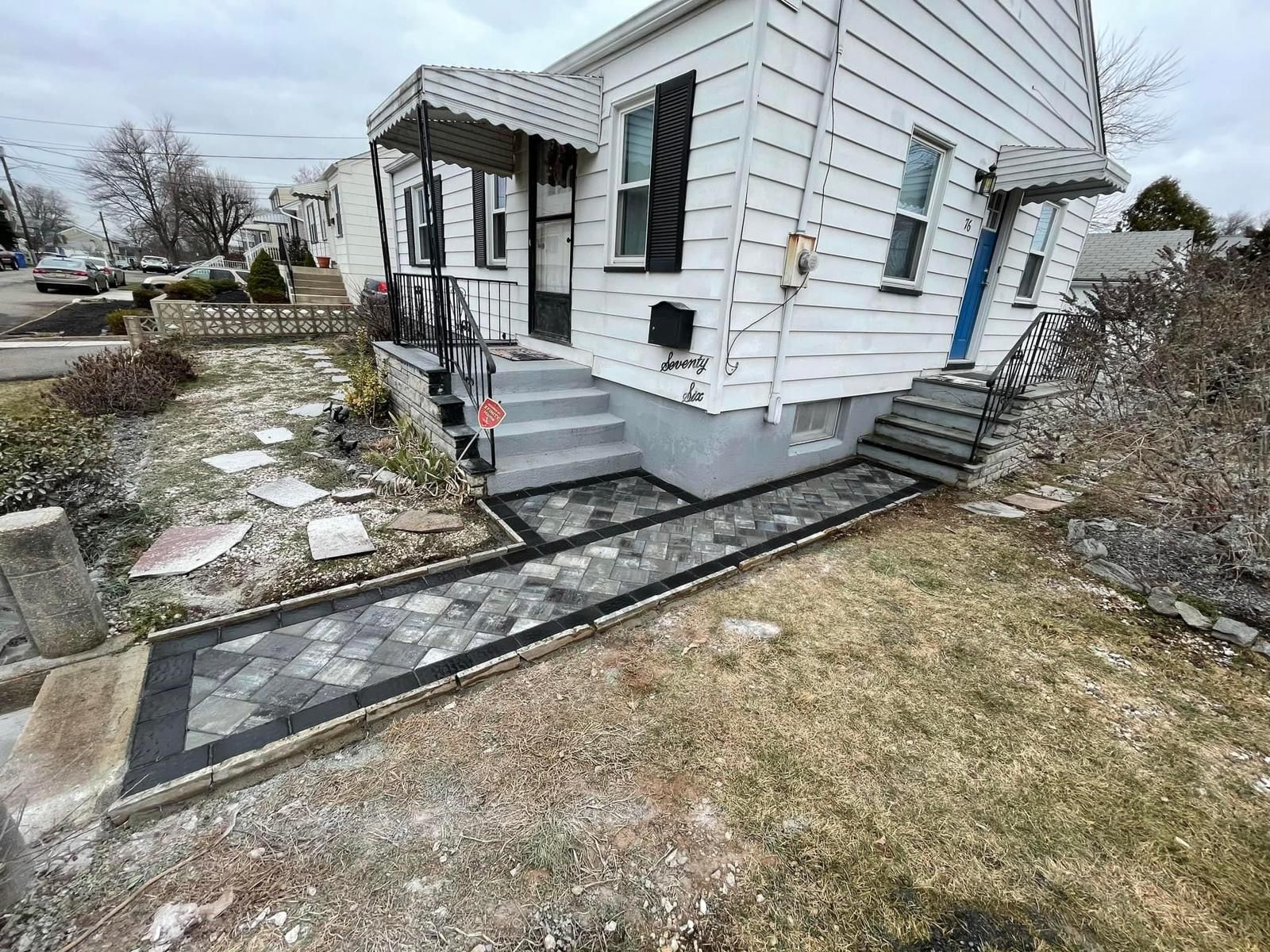 A white house with stairs and a walkway in front of it.
