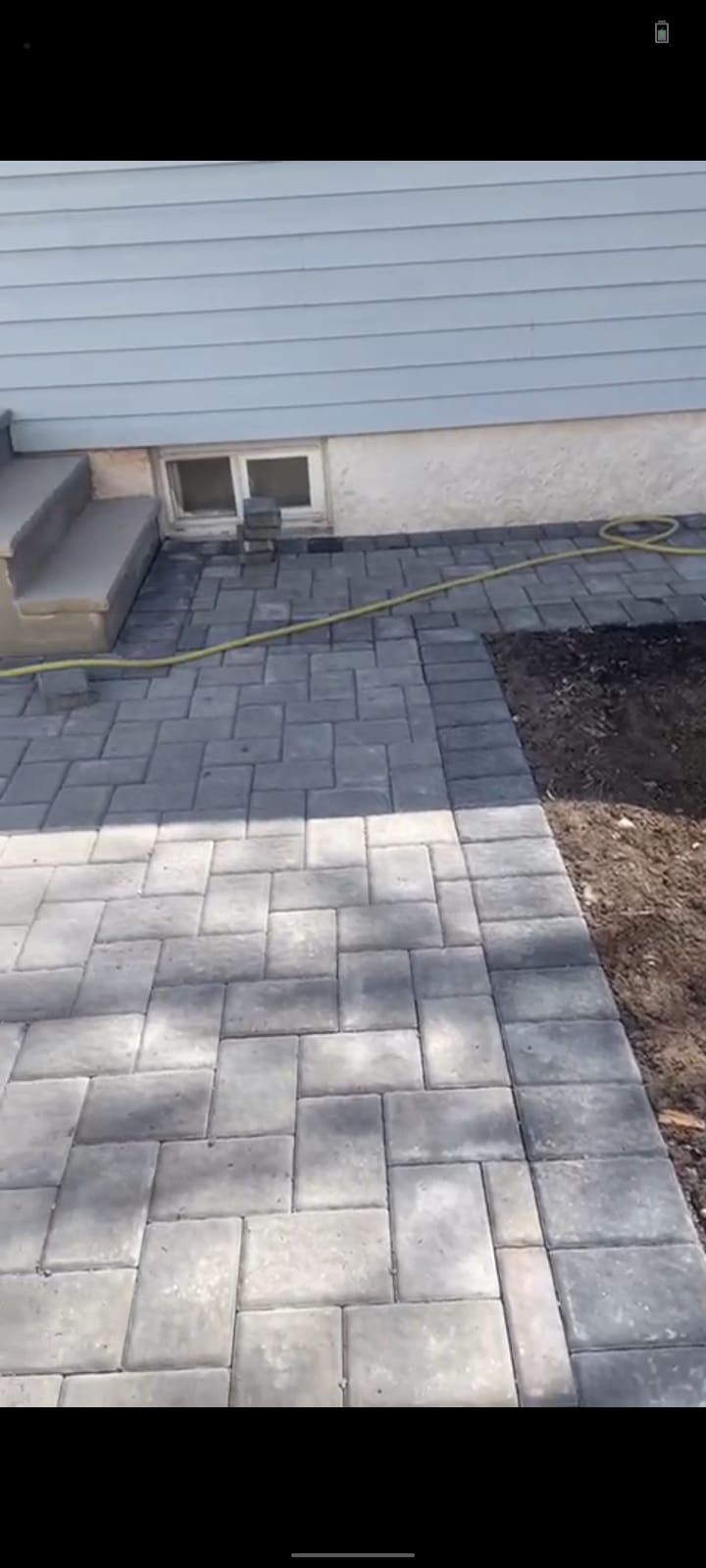 A brick walkway is being built in front of a house.