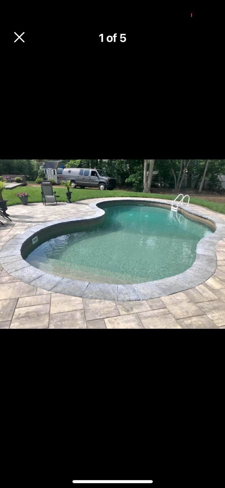 A large swimming pool is sitting on top of a brick patio.