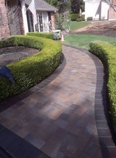 A brick walkway leading to a house with a flag in the background.