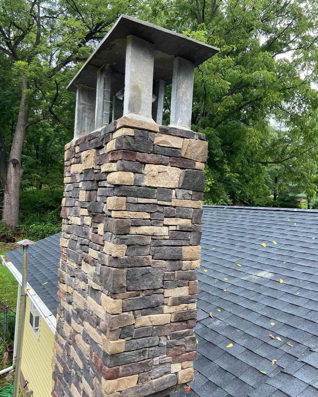 A stone chimney is sitting on top of a roof.