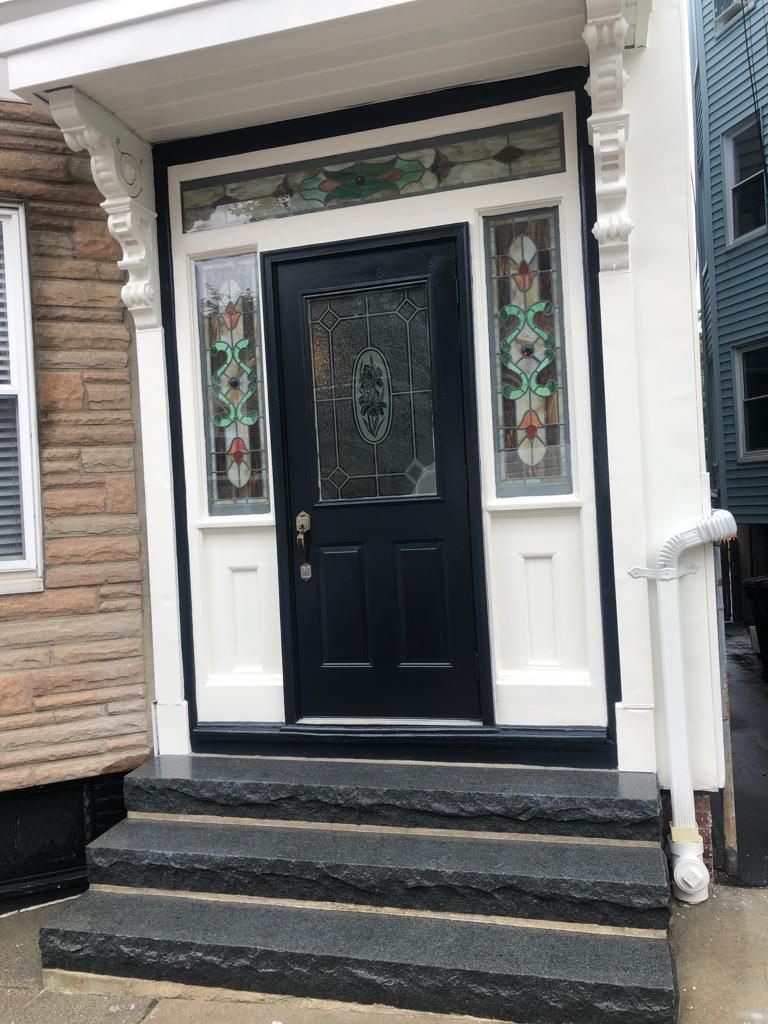 The front door of a house with a black door and steps