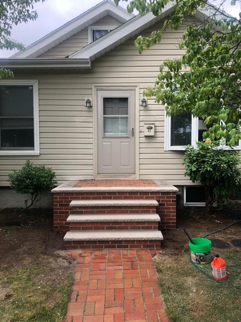 A house with a brick walkway leading to the front door.