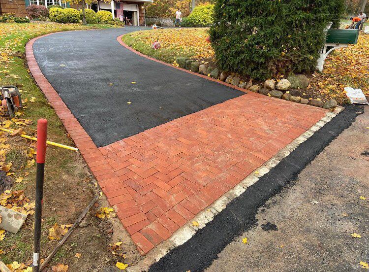 Driveway with black asphalt and brickwork border and paving.