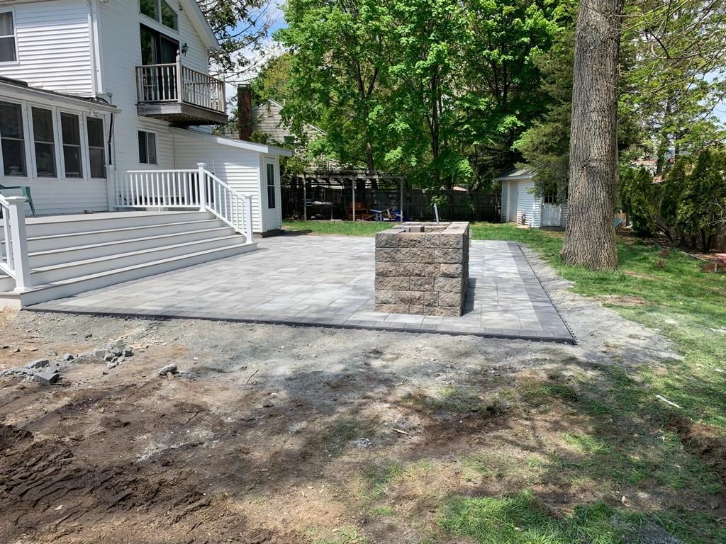A backyard with a patio and a fire pit in front of a house.