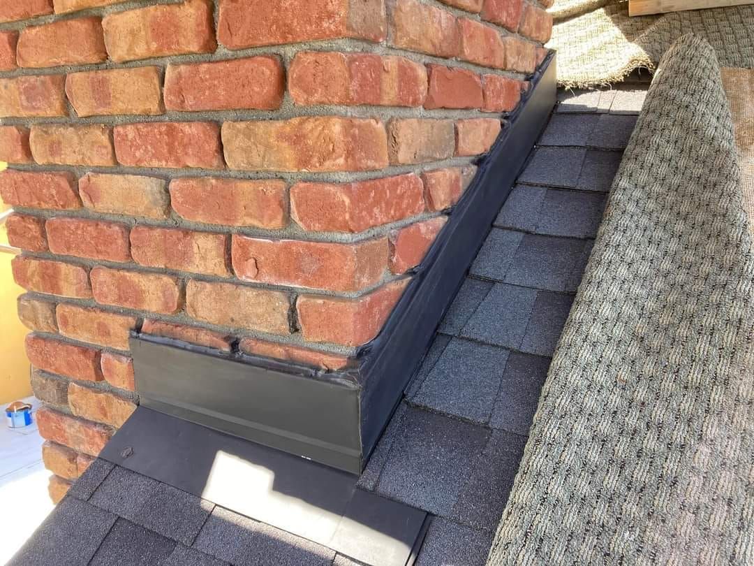 A brick chimney is sitting on top of a roof.