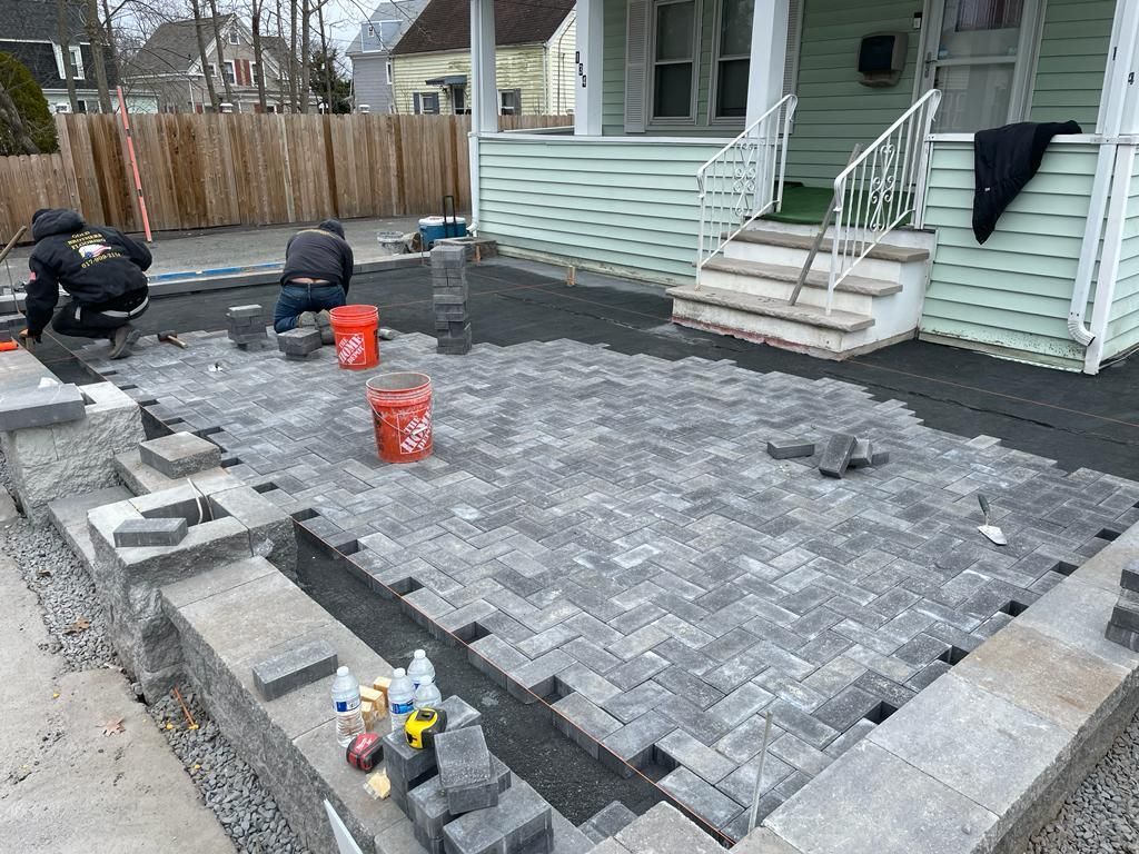 A group of men are working on a patio in front of a house.