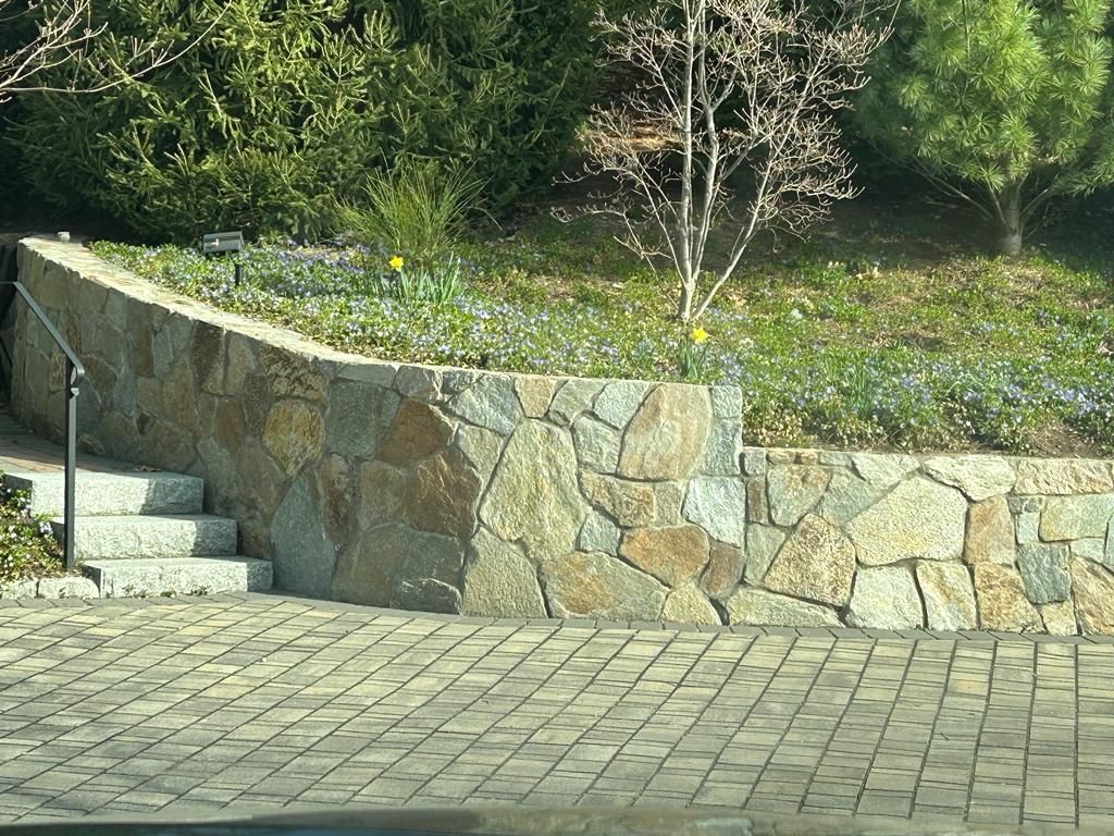 A stone wall with stairs leading up to it in a garden.