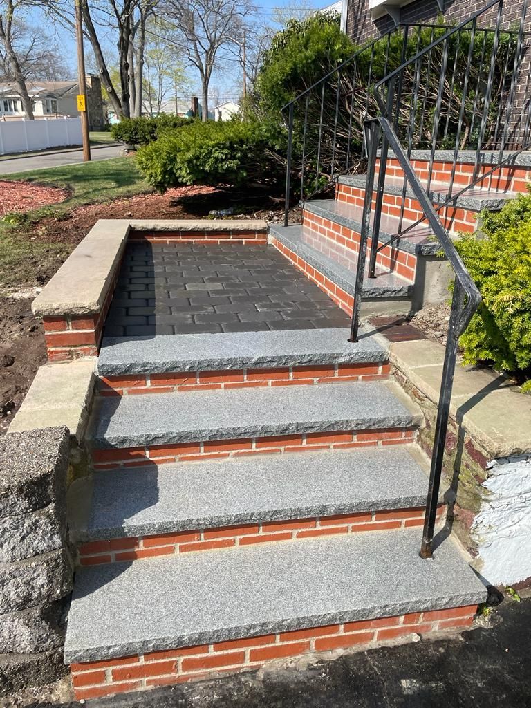 A set of stairs made of granite and brick with a metal railing.