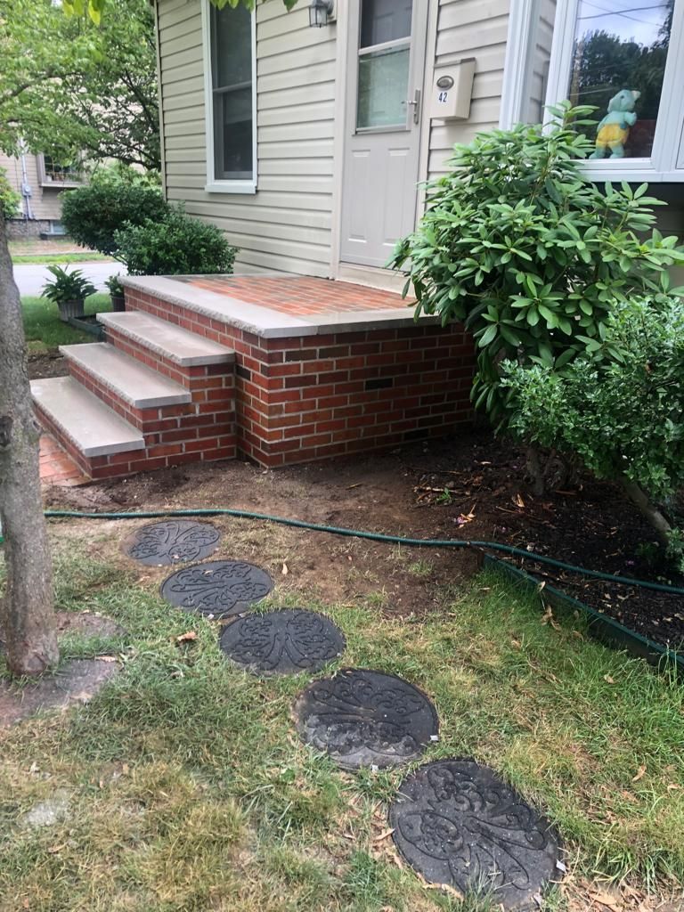 A house with a brick porch and steps in front of it.