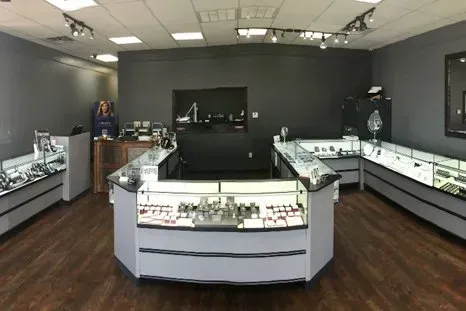 Jewelry store interior with gray walls, wood floors, and display cases filled with jewelry.