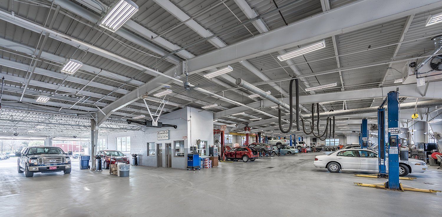 A large garage filled with cars being worked on by mechanics.