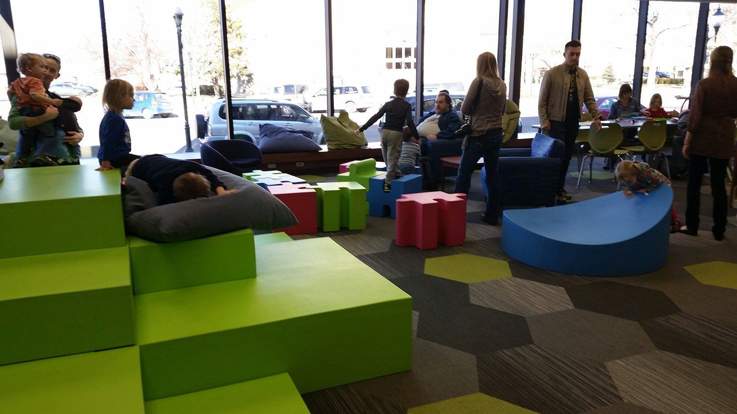 A group of people are playing in a room with green blocks