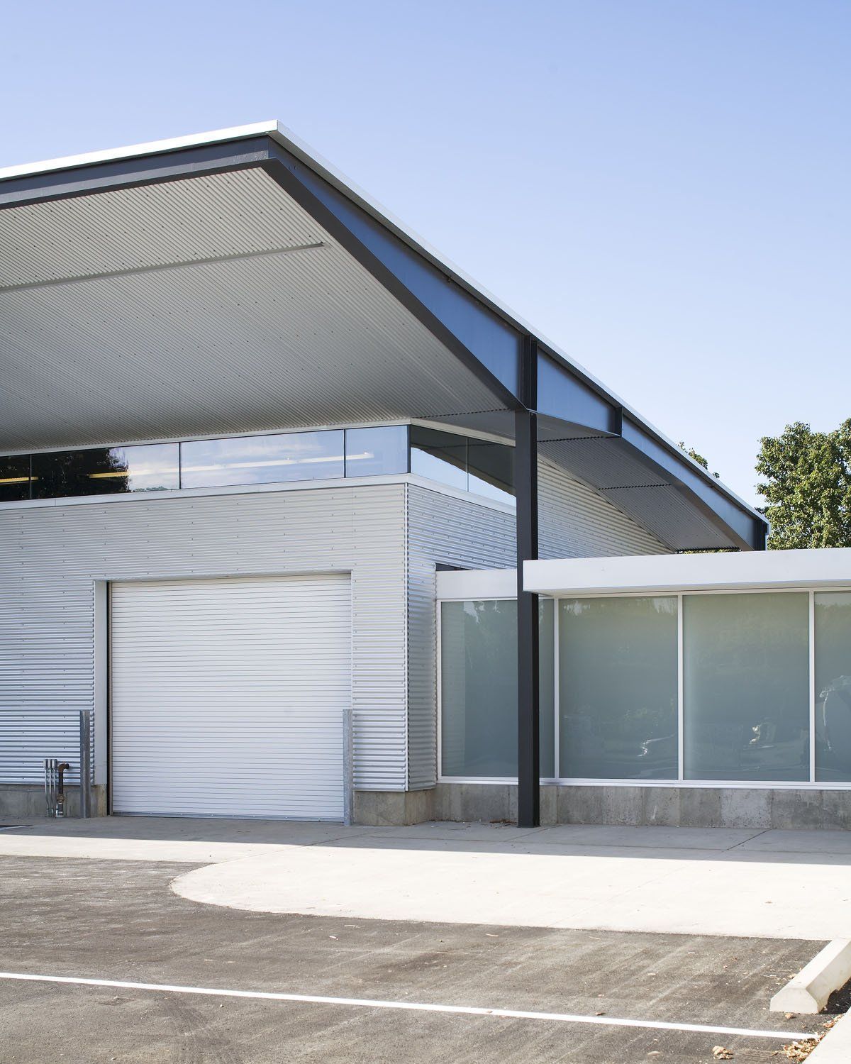 A white building with a black roof has a parking lot in front of it