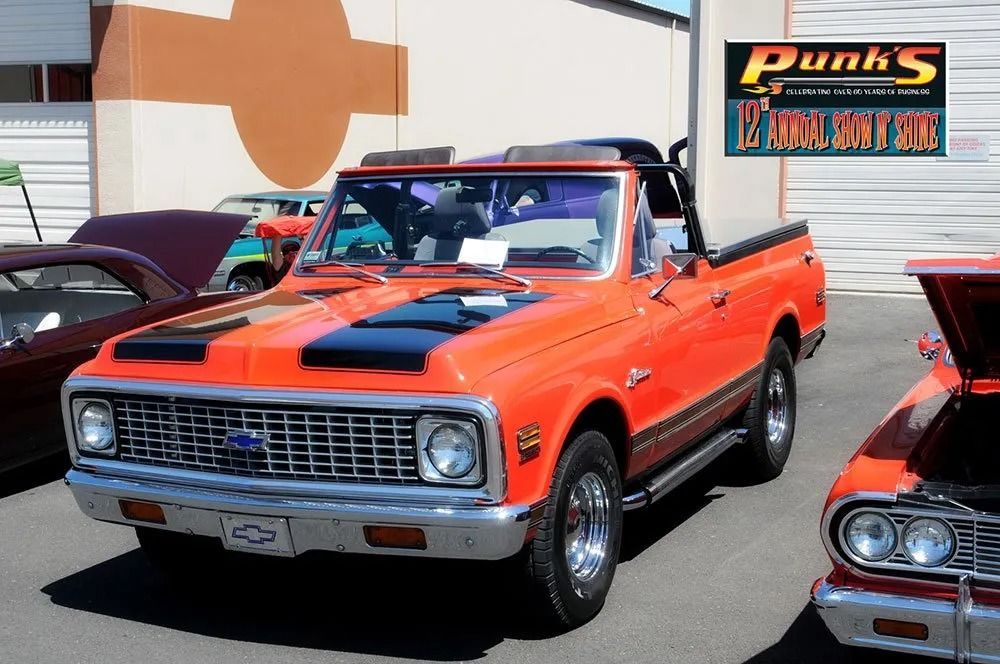 Orange vintage Chevrolet pickup truck at an outdoor car show.